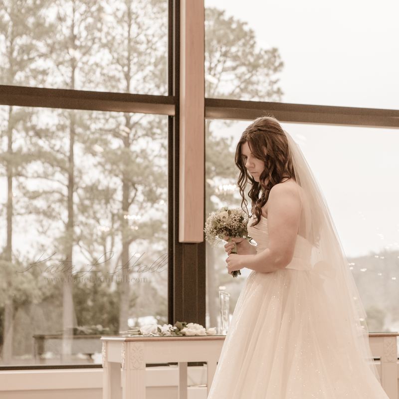 Bride with her bouquet beside tall windows
