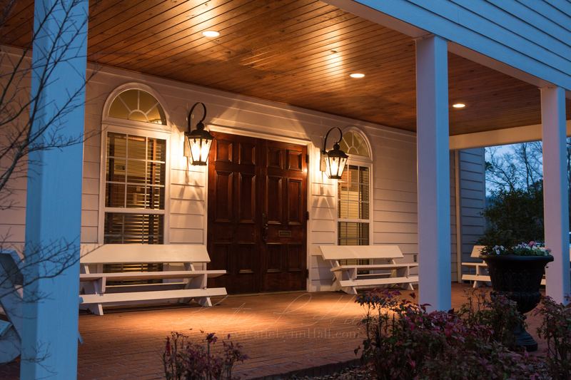 Covered porch with lantern lights and white benches at dusk